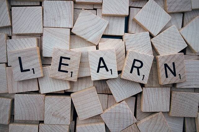 Scrabble Buchstaben auf einem Tisch. Die Buchstaben schreiben das Wort learn